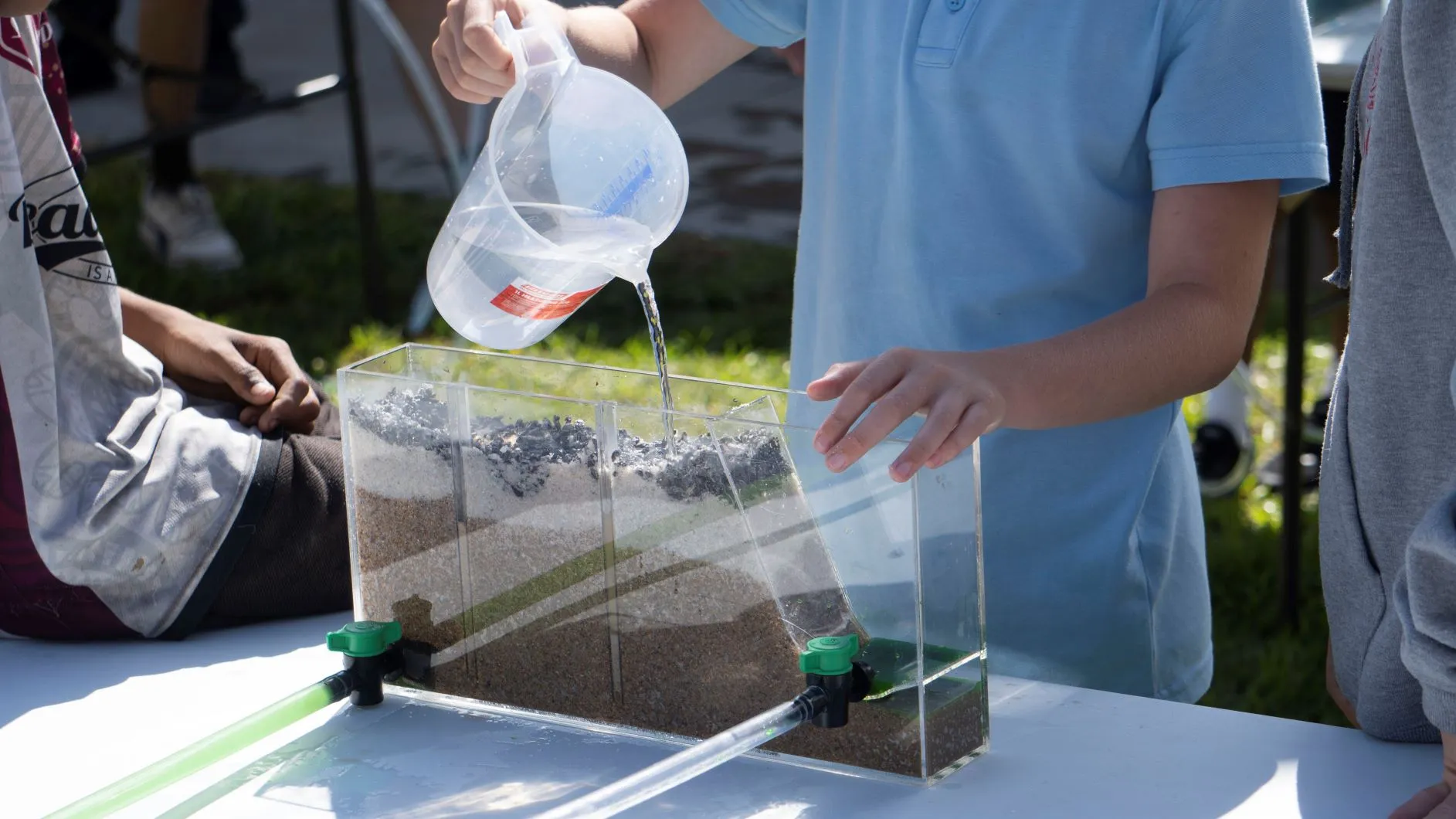 Bourke Public School students observe the flow of water below the surface, using an aquifer model they built from gravel and sand (October 2022)