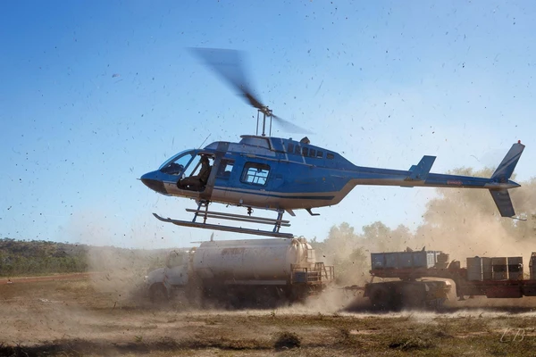 Helicopter landing after day of field work, kicking up dust and debris