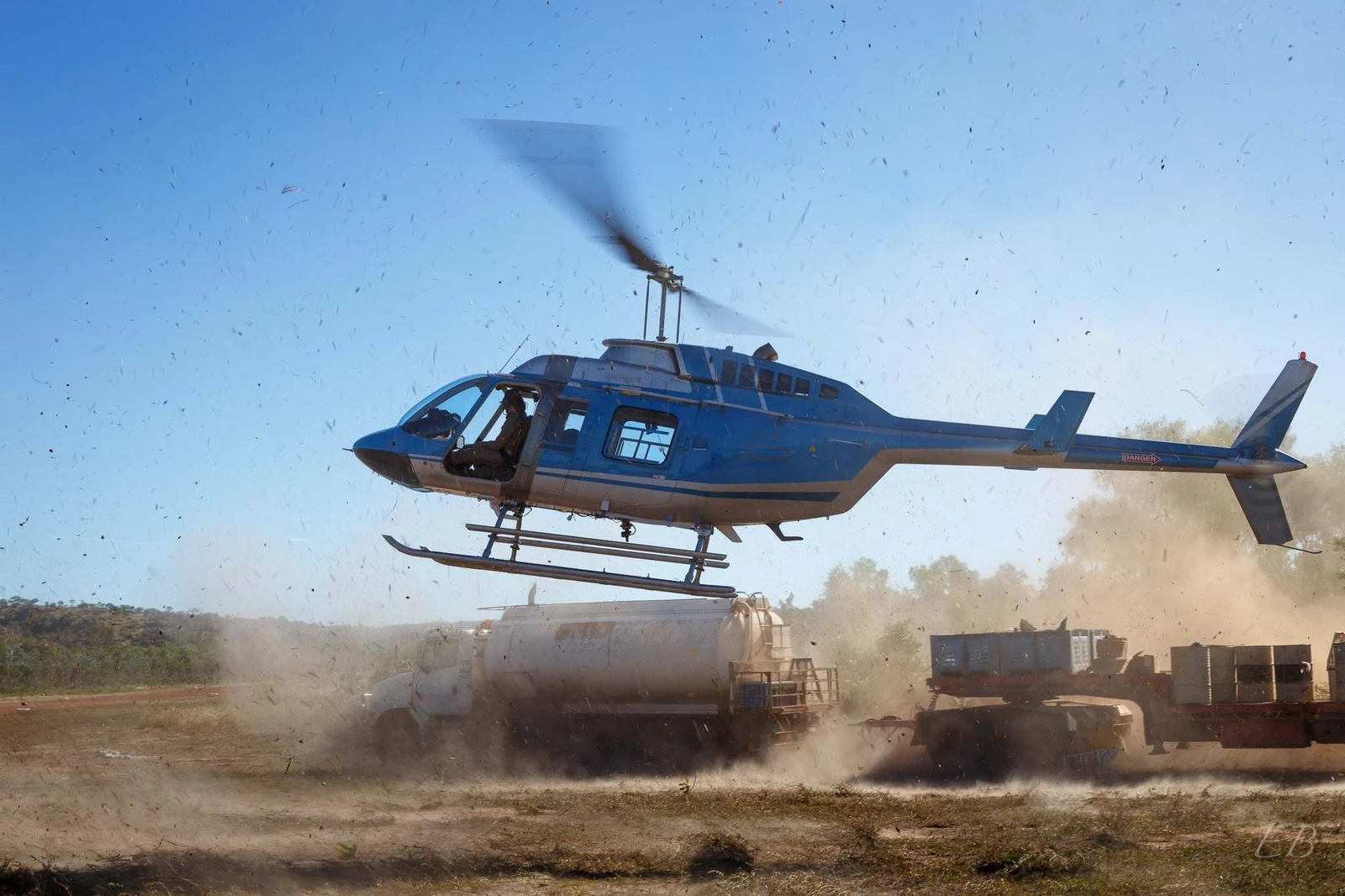 Helicopter landing after day of field work, kicking up dust and debris
